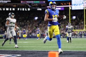 The cover for this NFL Odds week 17 article shows Puka Nacua #12 of the Los Angeles Rams scoring a touchdown during overtime against the Seattle Seahawks.
