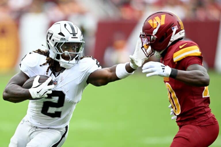 Ashton Jeanty #2 of the Las Vegas Raiders stiff arms Quan Martin #20 of the Washington Commanders