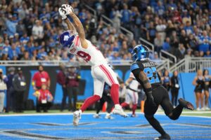 The cover for this NFL odds week 13 article shows Isaiah Hodgins #89 of the New York Giants catching a pass in front of Arthur Maulet #27 of the Detroit Lions