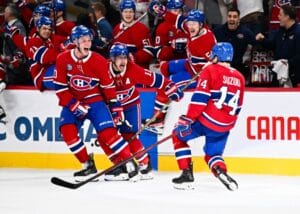 Nick Suzuki #14 of the Montreal Canadiens celebrates his game-winning overtime goal with teammates.