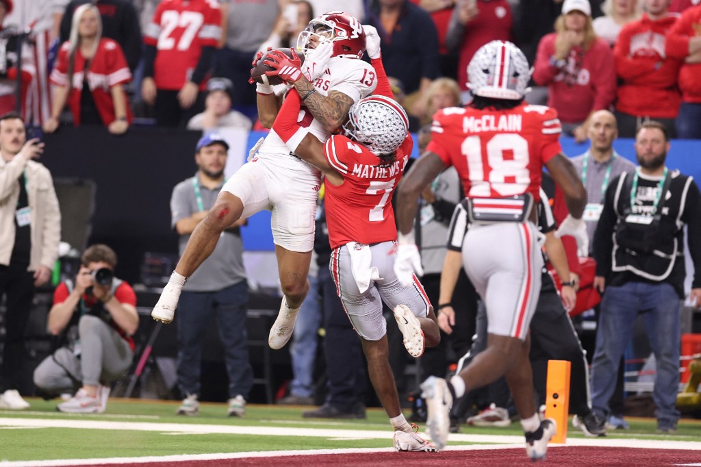 The cover for this college football conference winner predictions article shows Elijah Sarratt #13 of the Indiana Hoosiers catching a touchdown pass against the Ohio State Buckeyes.