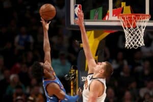 Shai Gilgeous-Alexander #2 of the Oklahoma City Thunder throws up a shot against Nikola Jokic #15 of the Denver Nuggets.