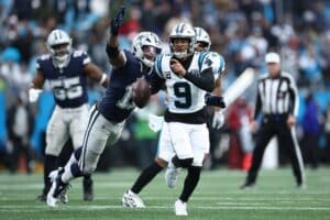 Bryce Young #9 of the Carolina Panthers carries the ball against Micah Parsons #11 of the Dallas Cowboys
