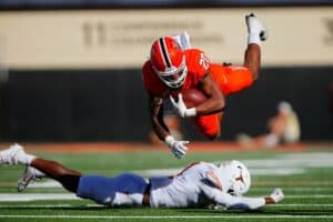 Running back Dominic Richardson #20 of the Oklahoma State Cowboys leaps over defensive lineman Justice Finkley #1 of the Texas Longhorns