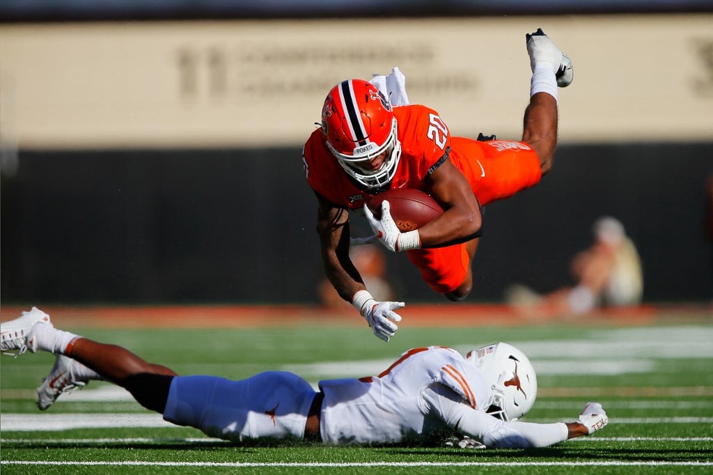 Running back Dominic Richardson #20 of the Oklahoma State Cowboys leaps over defensive lineman Justice Finkley #1 of the Texas Longhorns