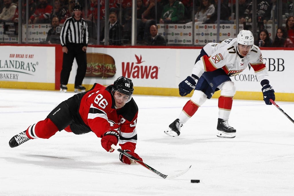 Jack Hughes #86 of the New Jersey Devils dives for the puck as Evan Rodrigues #17 of the Florida Panthers defends.