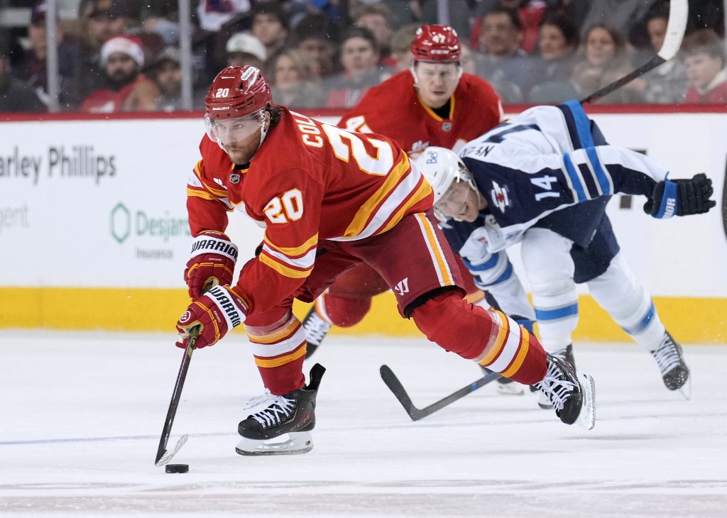 The cover for this NHL parlay picks today article shows Blake Coleman #20 of the Calgary Flames protects the puck from Gustav Nyquist #14 of the Winnipeg Jets.