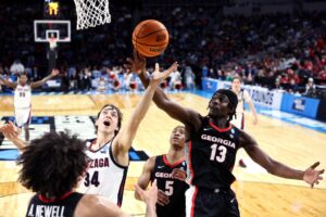 The cover for this college basketball picks today article shows Braden Huff #34 of the Gonzaga Bulldogs and Dylan James #13 of the Georgia Bulldogs reaching for a rebound.