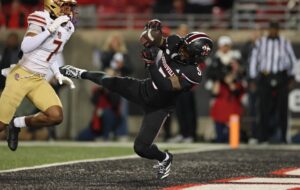 The cover for this Friday night college football article shows Caullin Lacy #5 of the Louisville Cardinals catching a pass for a touchdown against the Boston College Eagles