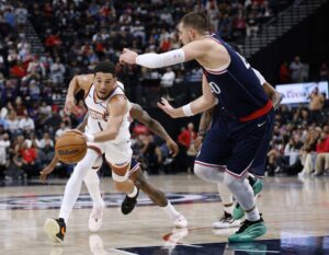 Phoenix Suns v Los Angeles Clippers - Oddstrader The cover of this NBA picks today article shows Devin Booker #1 of the Phoenix Suns dribbling in front of Ivica Zubac #40 of the LA Clippers