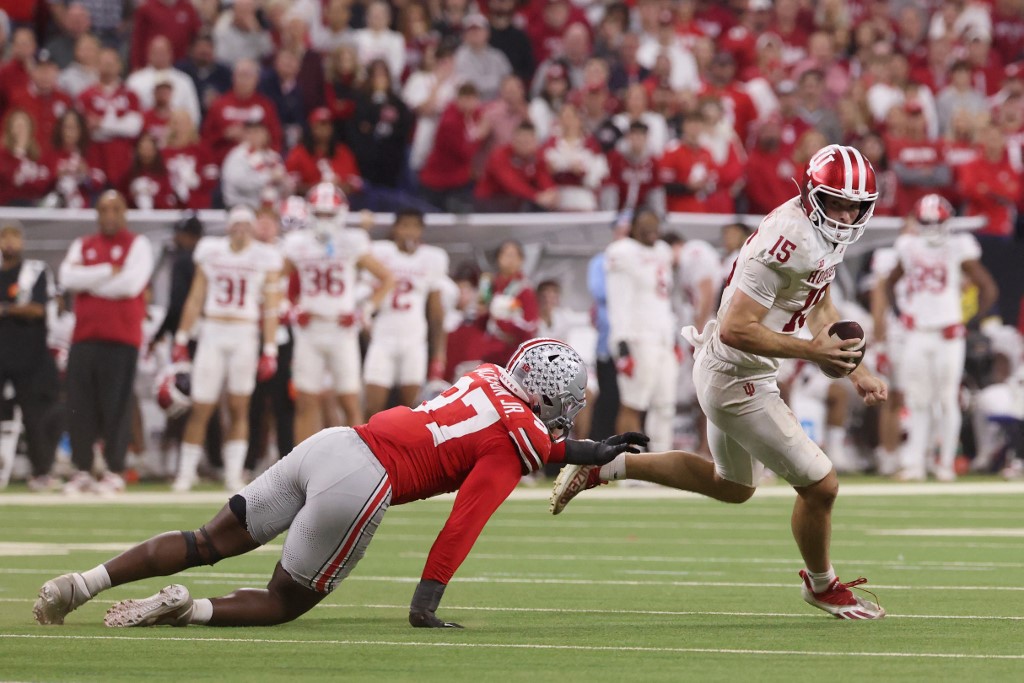 The cover for this NCAAF Heisman Trophy odds article shows Fernando Mendoza #15 of the Indiana Hoosiers scrambling with the ball, defended by Kenyatta Jackson Jr. #97 of the Ohio State Buckeyes.