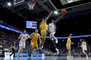 The cover for this college basketball picks today article shows Jasper Johnson #2 of the Kentucky Wildcats shoots the ball while defended by Rakim Chaney #0 of the Valparaiso Beacons