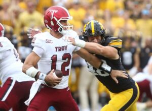 The cover for this Thursday college football picks article shows Defensive end Max Llewellyn #48 of the Iowa Hawkeyes making a sack during the second half against quarterback Matthew Caldwell #12 of the Troy Trojans