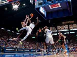 The cover for this college basketball picks today shows Melvin Council Jr. #14 of the Kansas Jayhawks lays the ball up against Landon Clark #8 of the Princeton Tigers.