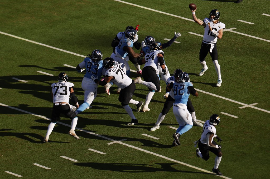 The cover for this Sunday night football picks article shows Trevor Lawrence #16 of the Jacksonville Jaguars dropping back to pass against the Tennessee Titans.