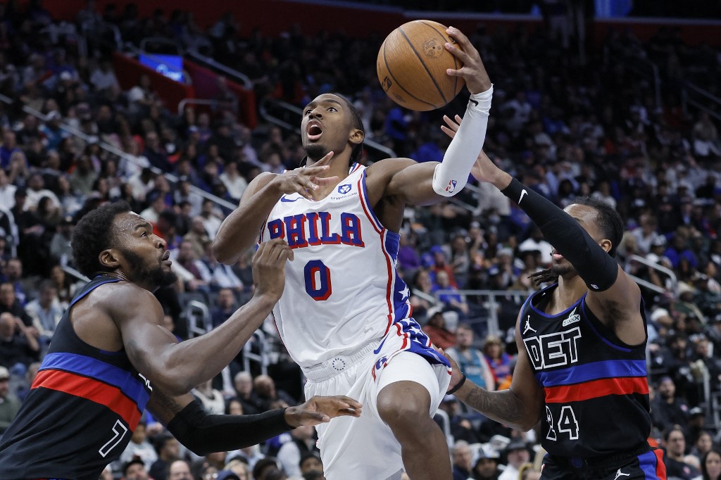 The cover for this NBA picks today article shows Tyrese Maxey #0 of the Philadelphia 76ers going to the basket between Paul Reed #7 and Daniss Jenkins #24 of the Detroit Pistons.