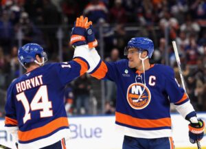 Bo Horvat #14 and Anders Lee #27 of the New York Islanders celebrate victory over the Seattle Kraken.