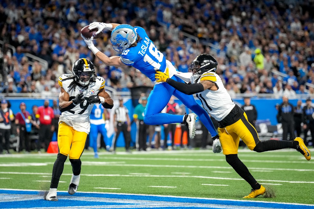 The cover for this Christmas Day football article shows Isaac Teslaa #18 of the Detroit Lions catching a pass over Kyle Dugger #29 and Chuck Clark #21 of the Pittsburgh Steelers for a touchdown during.