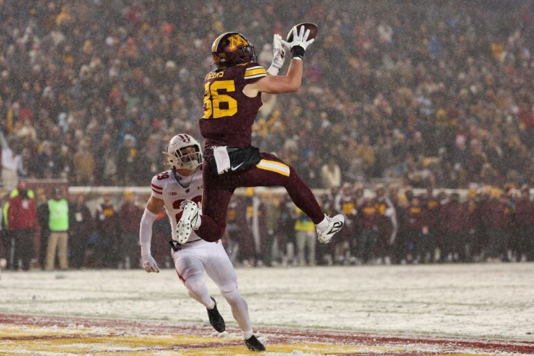Wisconsin v Minnesota - Oddstrader - Oddstrader The cover for this friday night college football bets article shows Jameson Geers #86 of the Minnesota Golden Gophers catching a touchdown pass against Matt Jung #29 of the Wisconsin Badgers.
