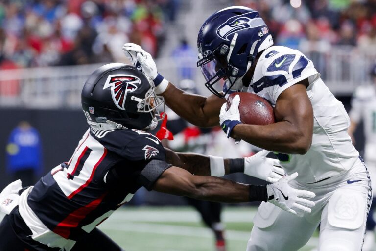 The cover for this Thursday night football picks article shows Kenneth Walker III #9 of the Seattle Seahawks stiffing arms against Dee Alford #20 of the Atlanta Falcons.