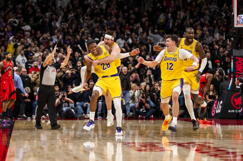 The cover for this NBA player props today article shows Rui Hachimura #28 of the Los Angeles Lakers celebrating with teammates Austin Reaves #15, Jake LaRavia #12 and Deandre Ayton #5 after making the game winning three-point shot against the Toronto Raptors.