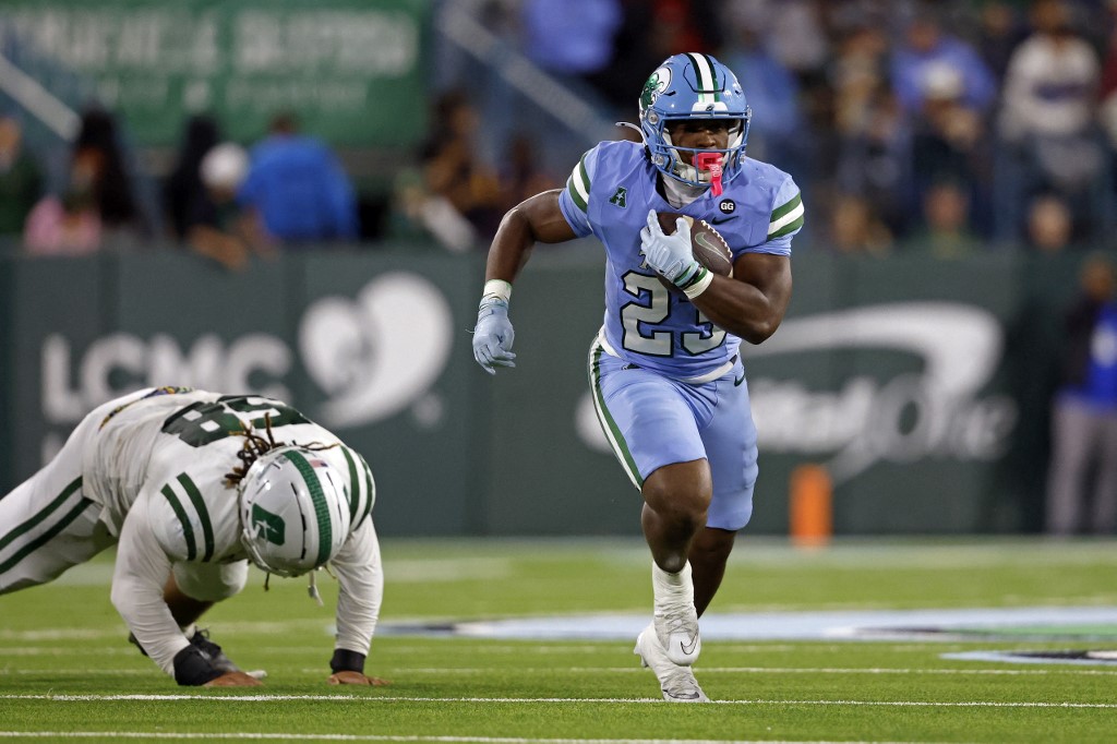 The cover for this college football player props bowls article shows Running back Javin Gordon #23 of the Tulane Green Wave running past defensive lineman Xavier Miles #58 of the Charlotte 49ers.