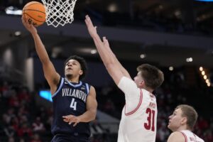 2025 Milwaukee Hoops Showdown Villanova v Wisconsin - Oddstrader The cover for this college basketball picks today article shows Tyler Perkins #4 of the Villanova Wildcats shooting the ball against Nolan Winter #31 of the Wisconsin Badgers.
