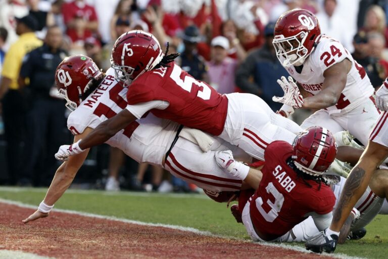 John Mateer #10 of the Oklahoma Sooners scores a touchdown as Dijon Lee Jr. #5 of the Alabama Crimson Tide defends.