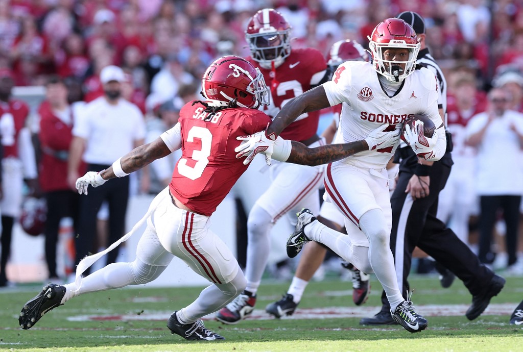 Deion Burks #4 of the Oklahoma Sooners runs with the ball against Keon Sabb #3 of the Alabama Crimson Tide.