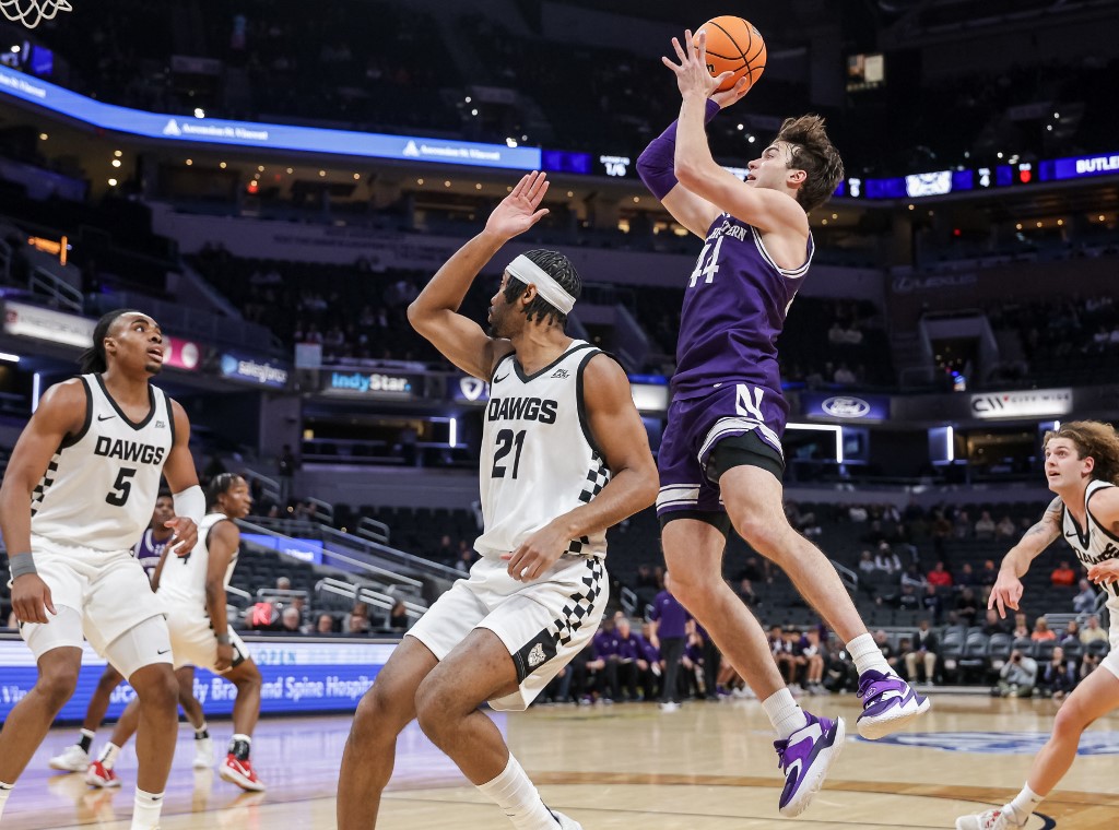 The cover for this college basketball picks today article shows Angelo Ciaravino #44 of the Northwestern Wildcats shooting the ball against Yohan Traore #21 of the Butler Bulldogs.