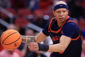 The cover for this college basketball picks today article shows Jacari White #6 of the Virginia Cavaliers driving to the basket during the first half against the Louisville Cardinals.