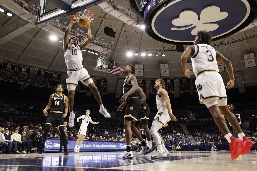 The cover for this college basketball picks today article shows Jalen Haralson #10 of the Notre Dame Fighting Irish dunking the ball against the Missouri Tigers.