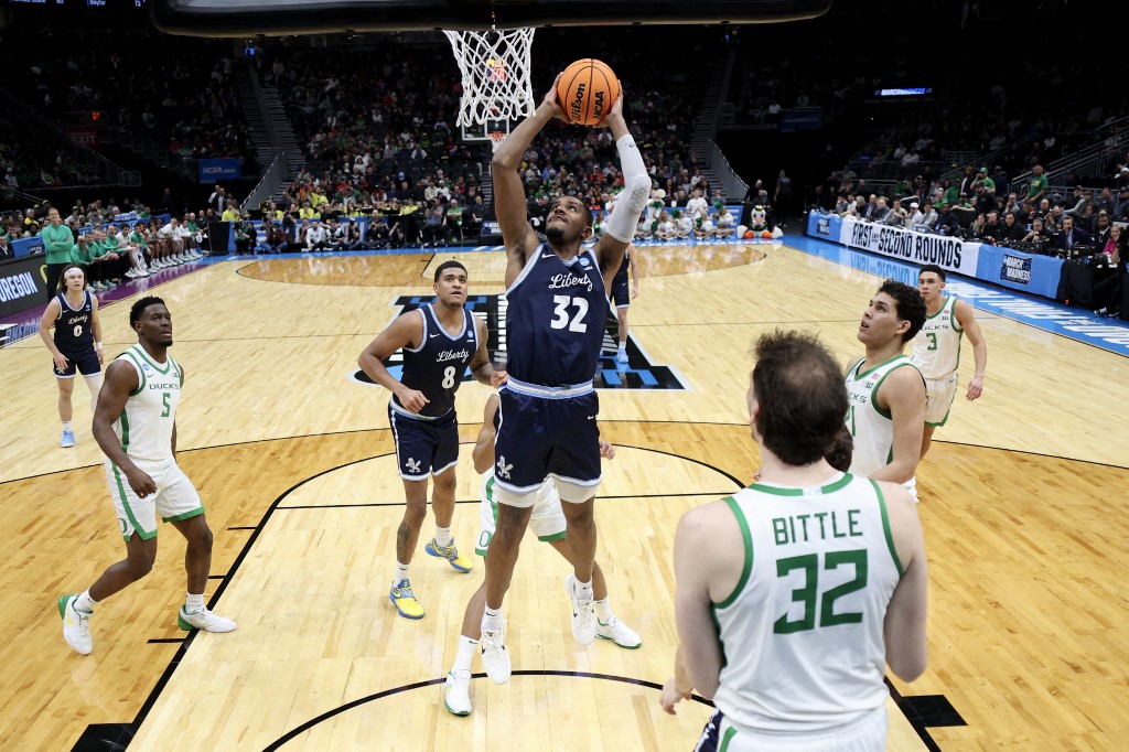 The cover for this college basketball picks today article shows Jayvon Maughmer #32 of the Liberty Flames dunking the ball during the second half of a game against the Oregon Ducks.