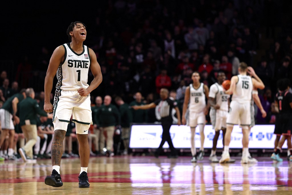 The cover for this college basketball picks today article shows Jeremy Fears Jr. #1 of the Michigan State Spartans reacting during overtime against the Rutgers Scarlet Knights.
