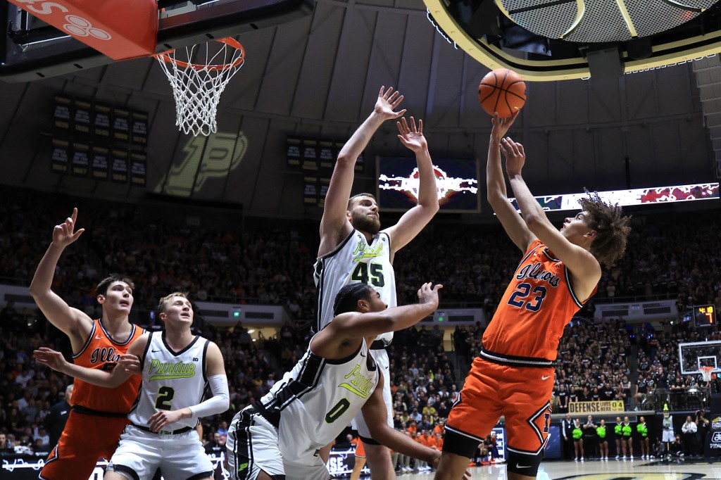 The cover for this college basketball picks today article shows Keaton Wagler #23 of the Illinois Fighting Illini taking a shot over Oscar Cluff #45 of the Purdue Boilermakers.