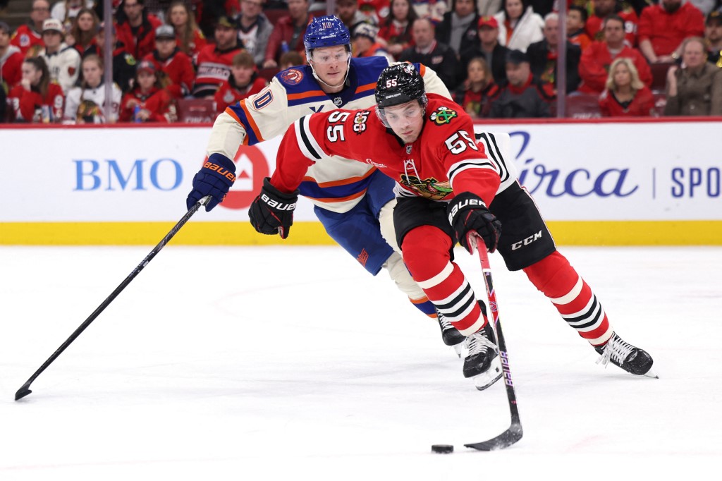 The cover for this NHL picks today article shows Artyom Levshunov #55 of the Chicago Blackhawks skating the puck ahead of Trent Frederic #10 of the Edmonton Oilers.