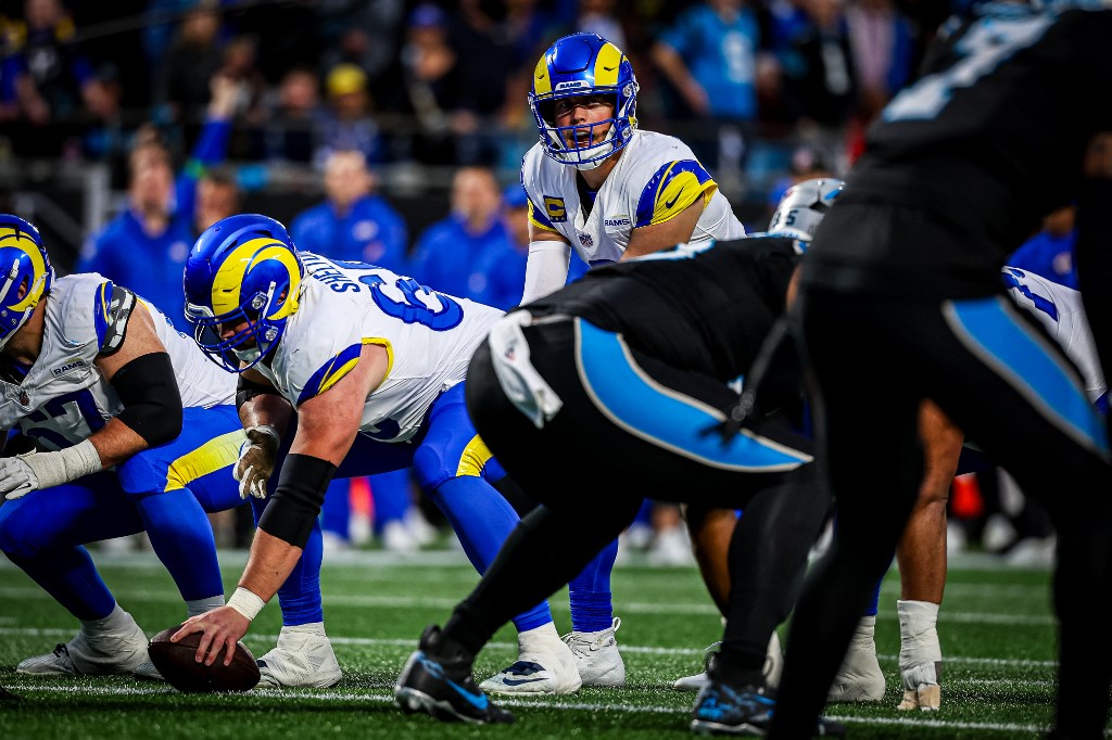 The cover for this NFL Sunday divisional round picks article shows Matthew Stafford #9 of the Los Angeles Rams snapping the ball during the first half of the NFC Wild Card Playoff game against the Carolina Panthers.