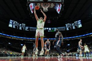The cover for this college basketball picks today article shows Nate Bittle #32 of the Oregon Ducks shooting as Graham Ike #15 of the Gonzaga Bulldogs looks on.