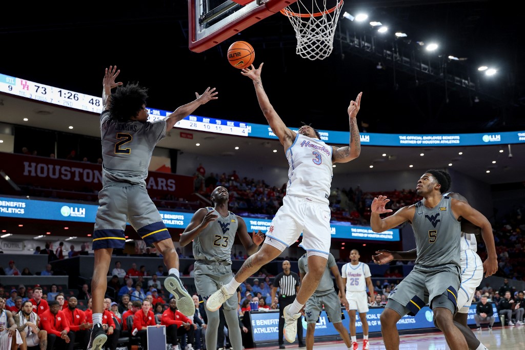 The cover for this college basketball picks today article shows Ramon Walker Jr. #3 of the Houston Cougars shooting against Amir Jenkins #2 of the West Virginia Mountaineers.