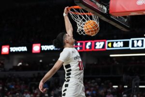 The cover for this college basketball picks today article shows Shon Abaev #10 of the Cincinnati Bearcats dunking the ball in the first half against the Dayton Flyers.