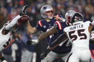 The cover for this NFL championship round odds article shows Will Anderson Jr. #51 of the Houston Texans forcing a fumble against Drake Maye #10 of the New England Patriots.