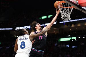 Jaime Jaquez Jr. #11 of the Miami Heat drives to the basket against Bones Hyland #8 of the Minnesota Timberwolves.