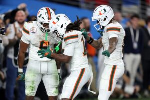 Malachi Toney #10 of the Miami Hurricanes (C) celebrates his touchdown with running back Charmar Brown #6 and Keelan Marion #0 during the 2025 College Football Playoff Semifinal at the VRBO Fiesta Bowl against the Ole Miss Rebels.