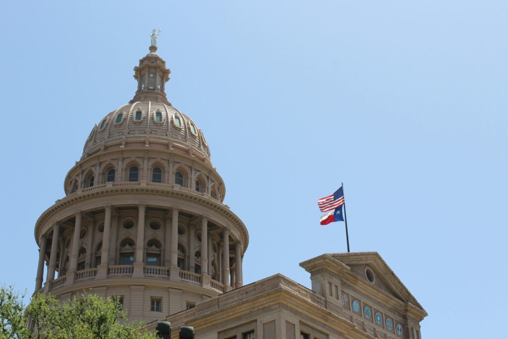 Texas state capitol building flying the American and Texas state flags