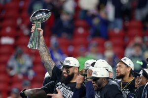 Abraham Lucas #72 of the Seattle Seahawks celebrates with the Vince Lombardi Trophy after winning Super Bowl LX against the New England Patriots.