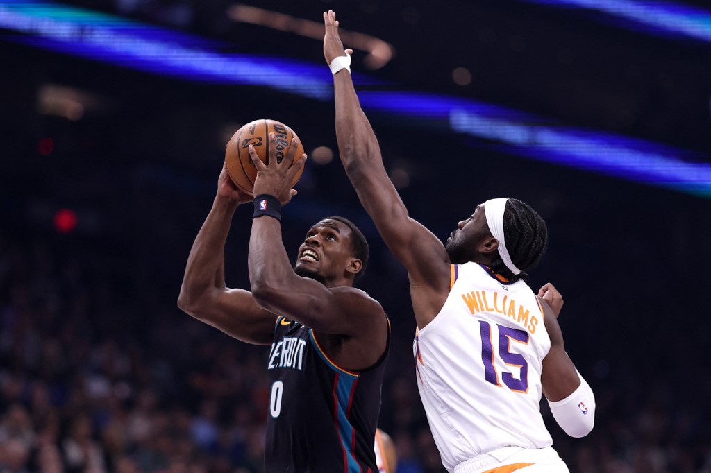 The cover for this NBA player props today article shows Jalen Duren #0 of the Detroit Pistons attempting a layup against Mark Williams #15 of the Phoenix Suns during the first half.