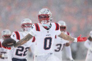 Christian Gonzalez #0 of the New England Patriots celebrates with teammates after intercepting a pass from Jarrett Stidham #8 of the Denver Broncos.
