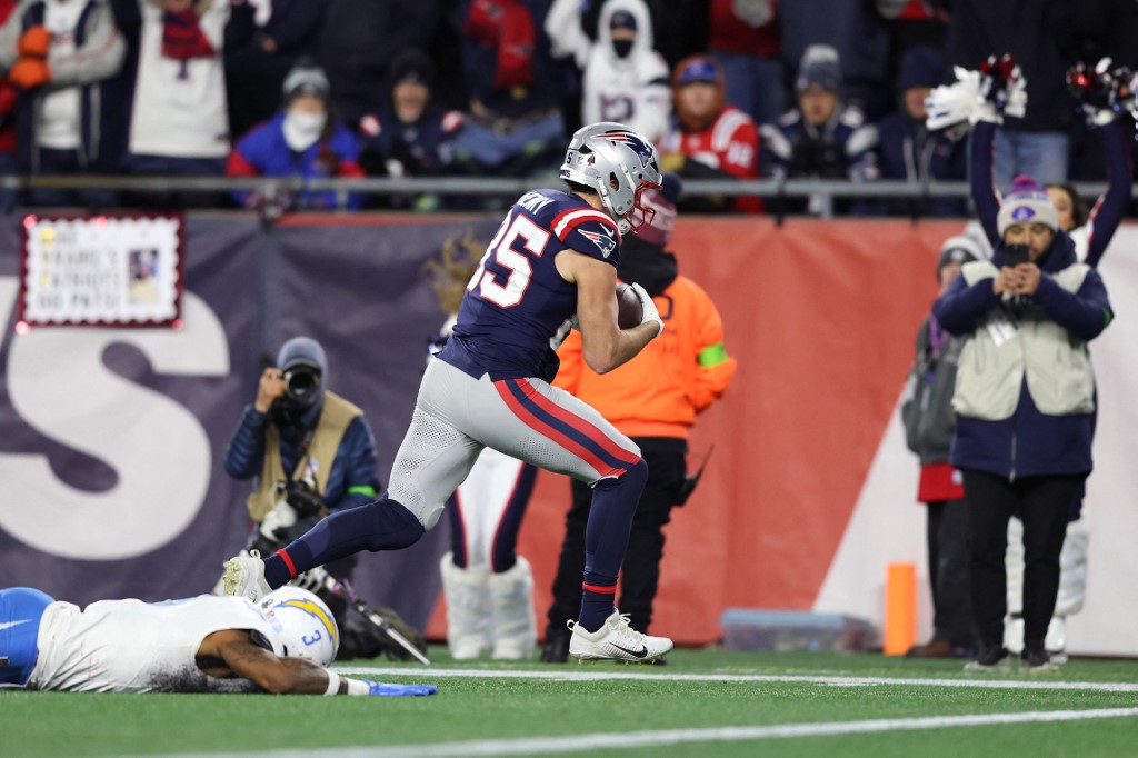 Hunter Henry #85 of the New England Patriots carries the ball after a reception for a touchdown defended by Derwin James Jr. #3 of the Los Angeles Chargers.