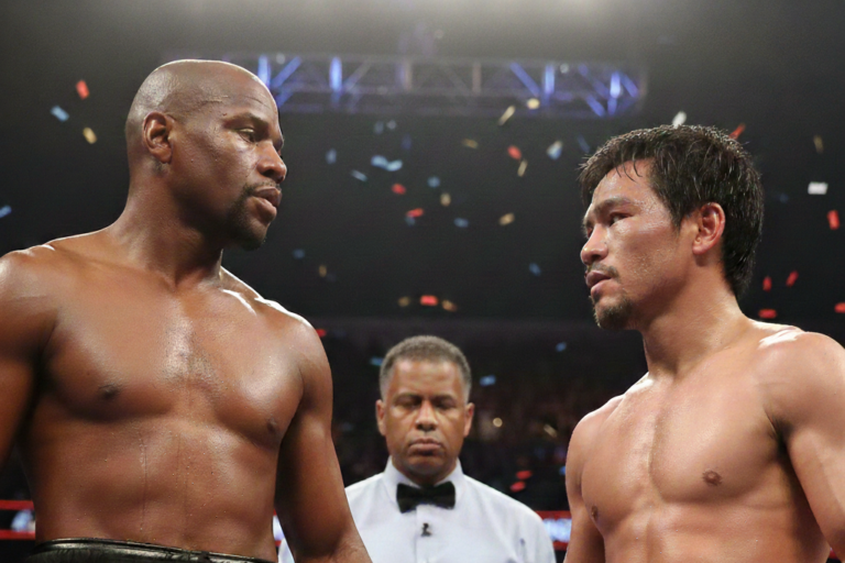 mayweather-vs-pacquiao-boxing-standoff-stare-downjpg - Oddstrader - Oddstrader A high-intensity, close-up frontal standoff between boxing legends Floyd Mayweather Jr. and Manny Pacquiao in a boxing ring with a referee in the background and confetti falling.
